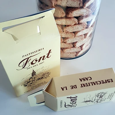 Carquinyolis dins un pot de vidre, al costat de les caixes de la Pastisseria Font